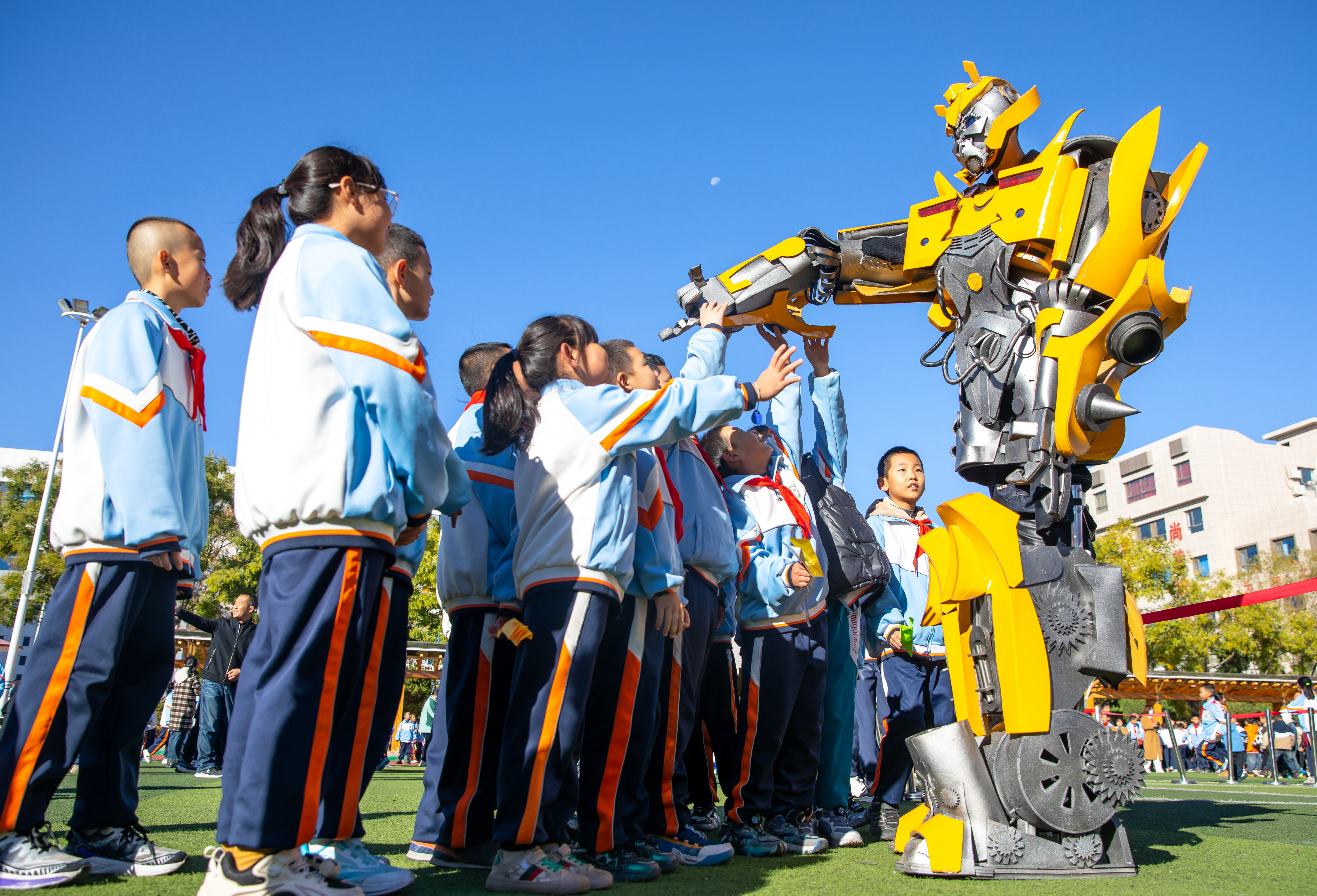 2024年10月22日，在甘肅省張掖市甘州區(qū)北街街小學(xué)科技大篷車(chē)嘉年華活動(dòng)上，學(xué)生與“大黃蜂”機(jī)器人互動(dòng)。楊瀟 攝.jpg