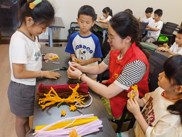 7月12日，在泰州市海陵區(qū)城東街道林湖社區(qū)，泰州市大浦小學(xué)“綠葉”暑期公益班的老師正在教孩子們一起做手工2（拍攝者：泰州市大浦中心小學(xué)  陳惠婷）.jpg